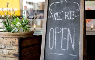 wooden we're open sign in front of small business