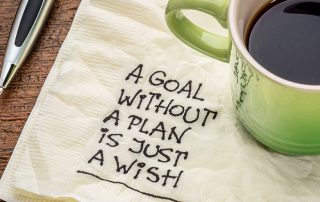 coffee cup on desk with napkin saying a goal without a plan is just a wish