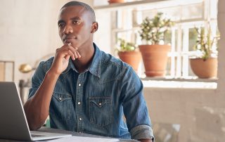 Thoughtful young African designer in his studio with laptop