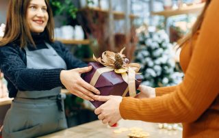 Female seller gives to customer christmas gift box